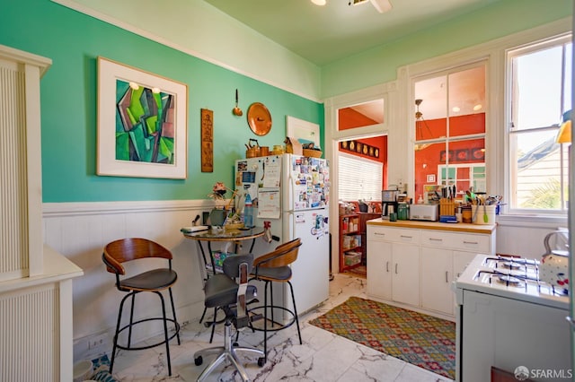 772-774 14th St, San Francisco, CA 94114 - kitchen with white appliances, light marble finish floors, healthy amount of natural light, wainscoting, and white cabinets