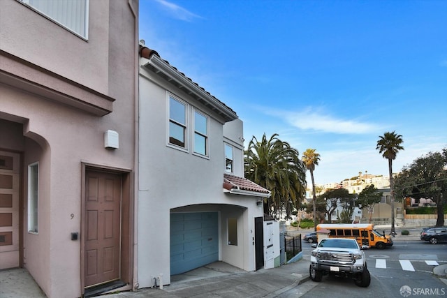 exterior space featuring stucco siding, an attached garage, and a tile roof