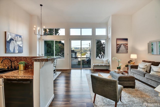 living room featuring baseboards, dark wood-type flooring, a high ceiling, and a chandelier