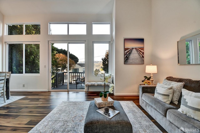 living room with dark wood finished floors, baseboards, and a towering ceiling