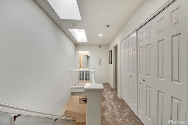 hall featuring a skylight, carpet flooring, recessed lighting, and baseboards