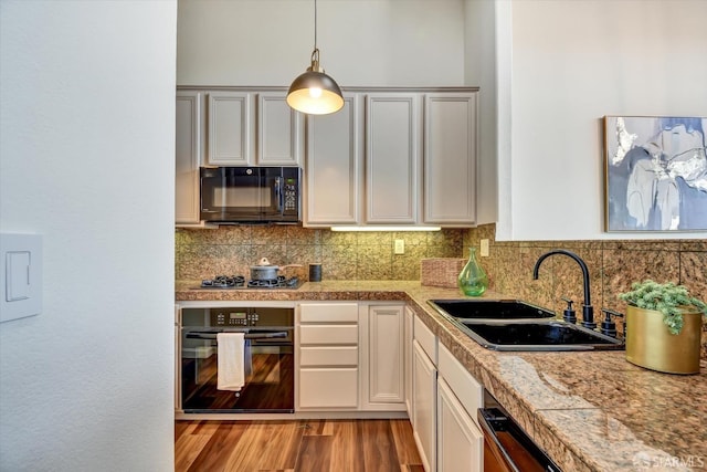 kitchen with tile countertops, a sink, black appliances, light wood-style floors, and backsplash