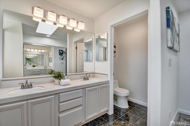 full bath featuring a sink, toilet, a skylight, and double vanity