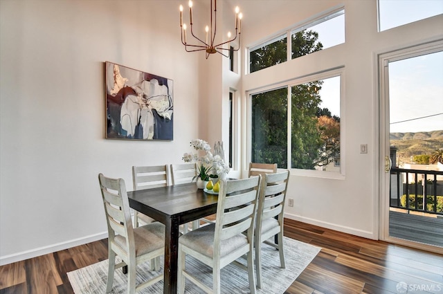 dining space featuring baseboards, an inviting chandelier, and wood finished floors