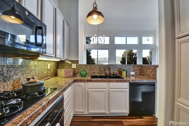 kitchen with a sink, black appliances, tile counters, a notable chandelier, and tasteful backsplash