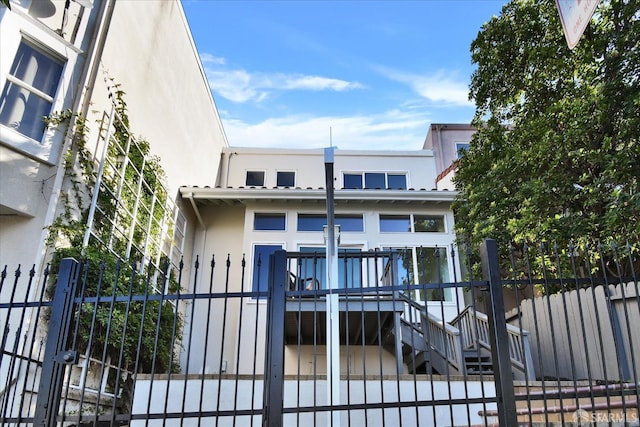 view of front of house featuring stucco siding, a wooden deck, and fence