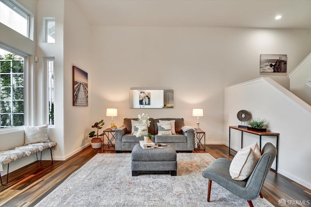 living area featuring recessed lighting, dark wood-style floors, baseboards, and a towering ceiling