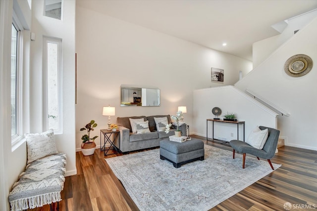 living area featuring baseboards, dark wood finished floors, stairs, recessed lighting, and a towering ceiling