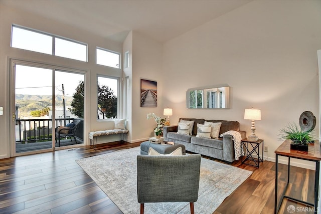 living room featuring baseboards, dark wood-style floors, and a towering ceiling