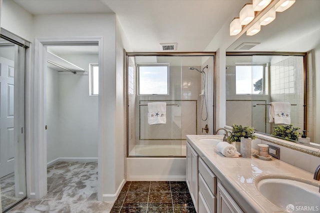 bathroom featuring bath / shower combo with glass door, a healthy amount of sunlight, and a sink