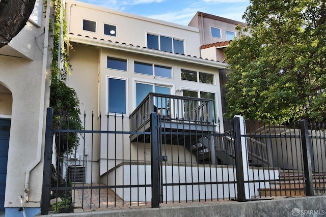 exterior space with stucco siding, central AC, and fence