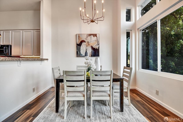 dining area with dark wood-style flooring, a wealth of natural light, and a chandelier