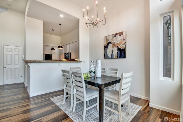 dining room featuring an inviting chandelier, dark wood-type flooring, baseboards, and a towering ceiling