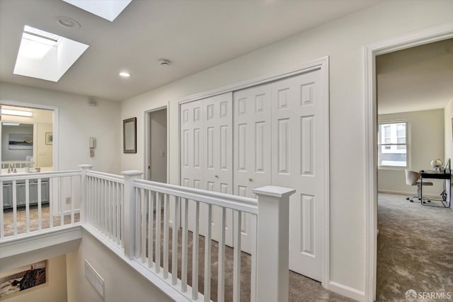 hallway with baseboards, carpet, an upstairs landing, recessed lighting, and a skylight