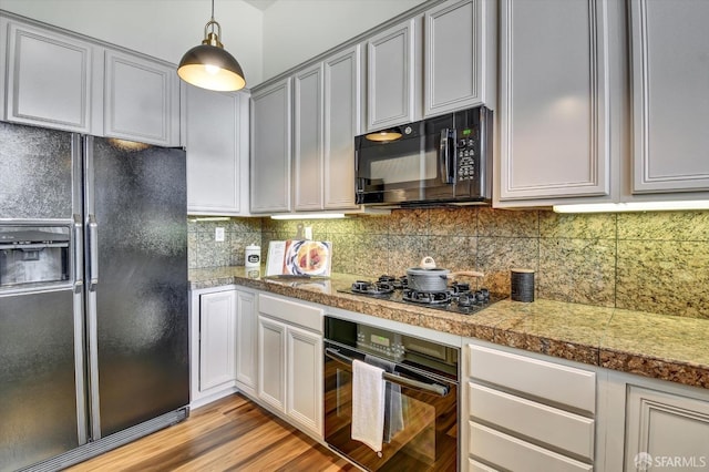 kitchen featuring black appliances, decorative light fixtures, tile countertops, light wood-style floors, and decorative backsplash