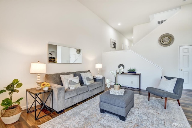 living room with visible vents, wood finished floors, recessed lighting, baseboards, and a towering ceiling