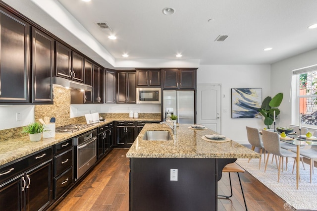 3069 Vittoria Loop, Dublin, CA 94568 - kitchen featuring appliances with stainless steel finishes, under cabinet range hood, a breakfast bar area, dark wood-type flooring, and recessed lighting