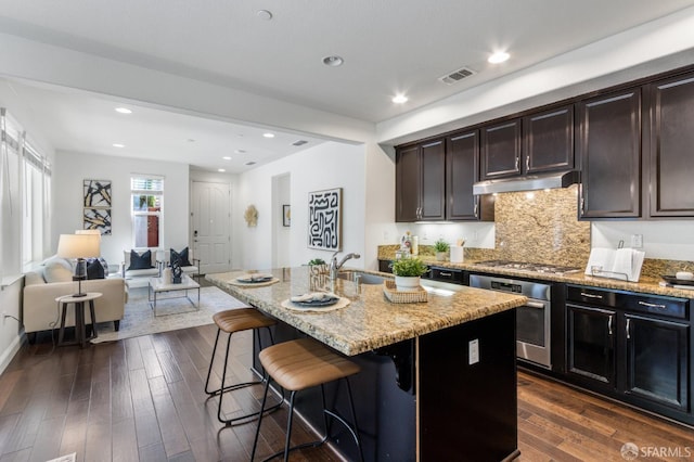 3069 Vittoria Loop, Dublin, CA 94568 - kitchen with appliances with stainless steel finishes, under cabinet range hood, light stone countertops, a breakfast bar area, and recessed lighting