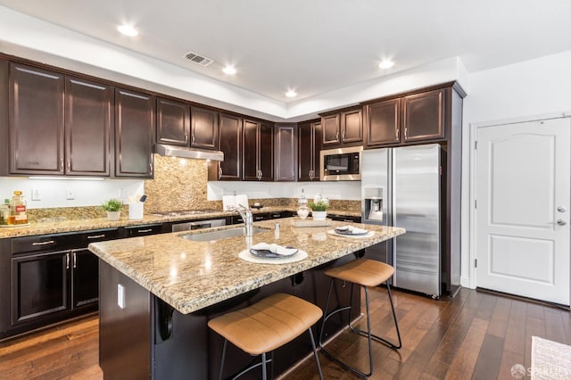 3069 Vittoria Loop, Dublin, CA 94568 - kitchen featuring stainless steel appliances, under cabinet range hood, dark wood-style flooring, a breakfast bar area, and dark brown cabinets