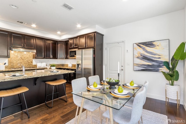 3069 Vittoria Loop, Dublin, CA 94568 - kitchen featuring stainless steel appliances, under cabinet range hood, dark wood-type flooring, dark brown cabinets, and light stone countertops