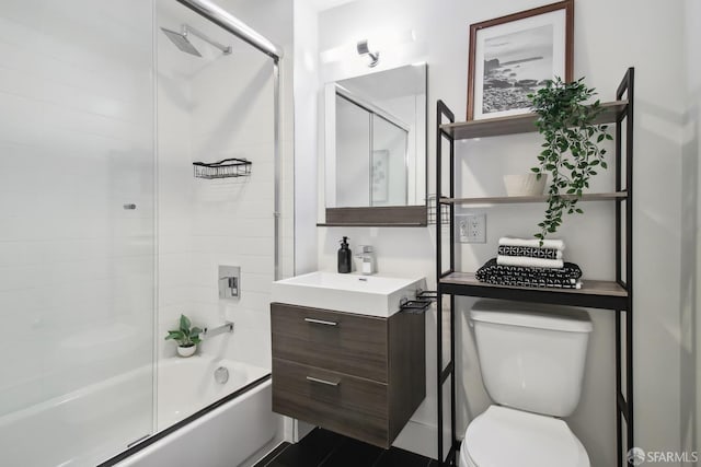 full bath with enclosed tub / shower combo, vanity, and toilet