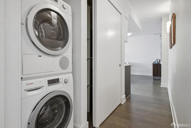 laundry area with laundry area, baseboards, wood finished floors, and stacked washer and clothes dryer