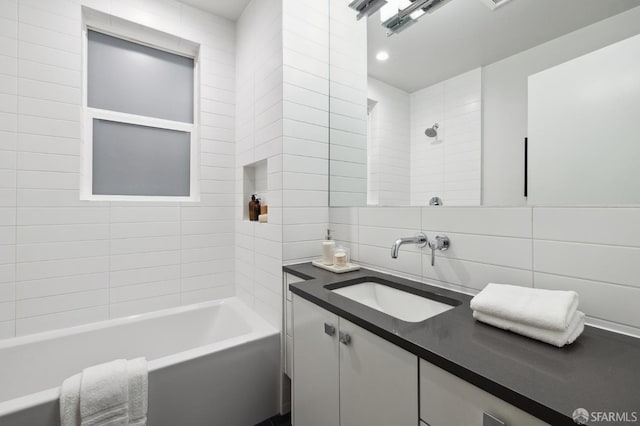 bathroom featuring tasteful backsplash, tiled shower / bath combo, vanity, and tile walls