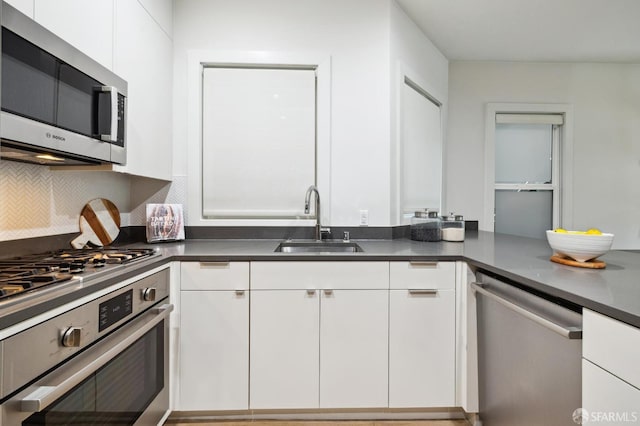 kitchen featuring appliances with stainless steel finishes, backsplash, sink, and white cabinets