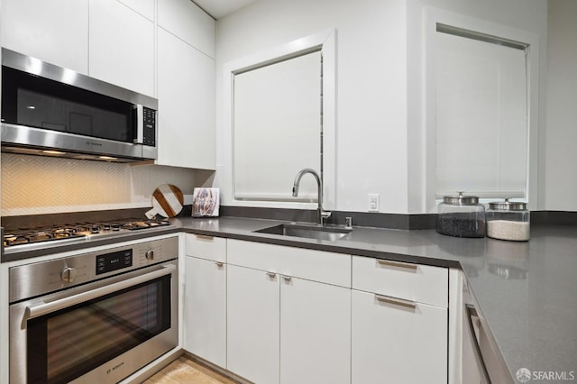 kitchen featuring decorative backsplash, appliances with stainless steel finishes, sink, and white cabinetry