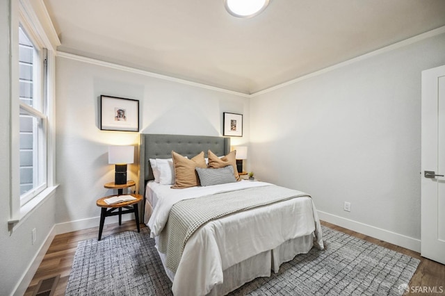 bedroom with multiple windows, crown molding, and hardwood / wood-style floors