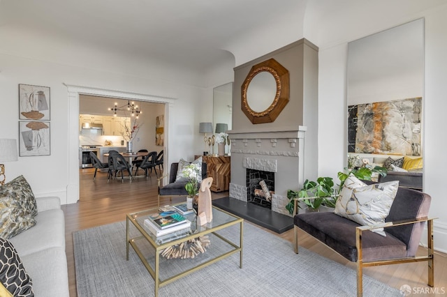 living area featuring a chandelier, a fireplace, and wood finished floors