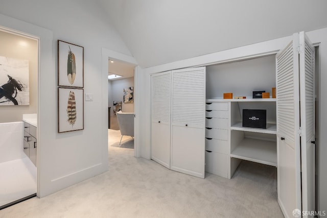 bedroom with vaulted ceiling, a closet, and light colored carpet