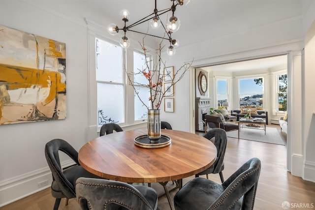 dining room featuring an inviting chandelier, a fireplace, and wood finished floors