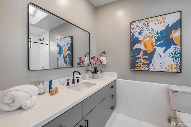 bathroom with a skylight, wainscoting, vanity, and toilet