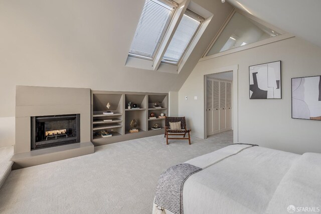 bedroom featuring light carpet, a fireplace with raised hearth, and lofted ceiling