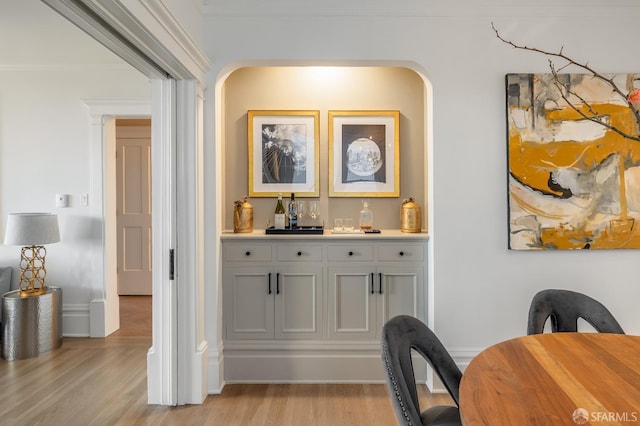 bar featuring ornamental molding, light wood-style flooring, and baseboards