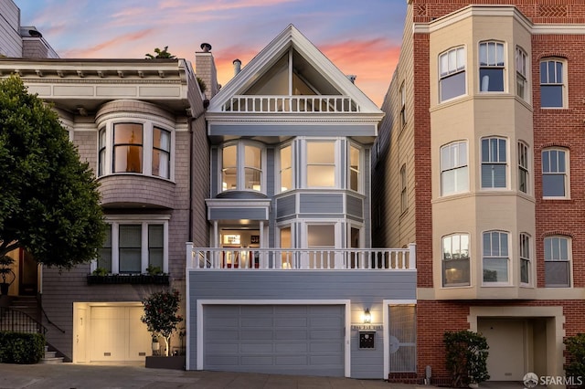 multi unit property featuring a balcony, a garage, and concrete driveway