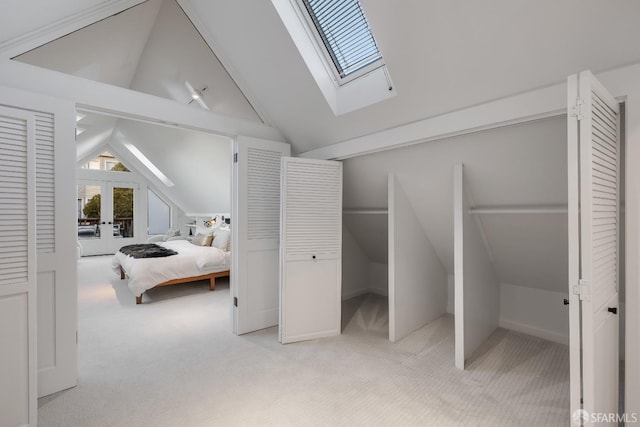 bedroom featuring light carpet, lofted ceiling with skylight, and french doors