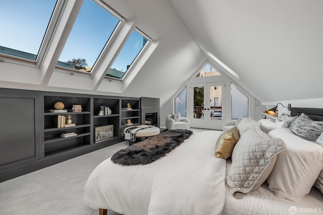 bedroom featuring carpet floors, access to exterior, french doors, a fireplace, and vaulted ceiling with skylight