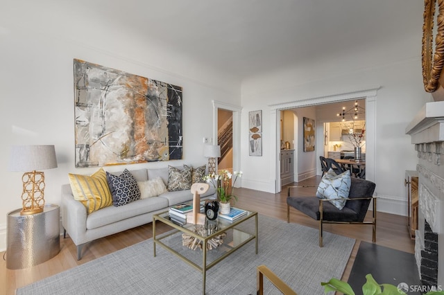 living room featuring baseboards, a fireplace with flush hearth, arched walkways, and wood finished floors