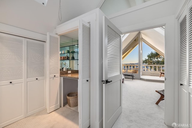 corridor featuring lofted ceiling and light carpet