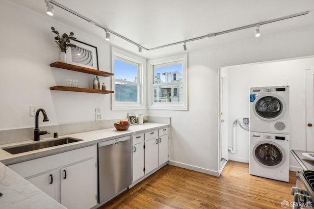 221 Lily St, San Francisco, CA 94102 - laundry room featuring track lighting, stacked washer / drying machine, light wood-type flooring, and baseboards