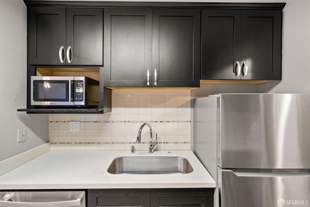 kitchen with light countertops, appliances with stainless steel finishes, a sink, and dark cabinets