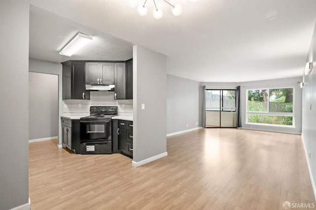 kitchen with open floor plan, black range with electric stovetop, light countertops, under cabinet range hood, and backsplash