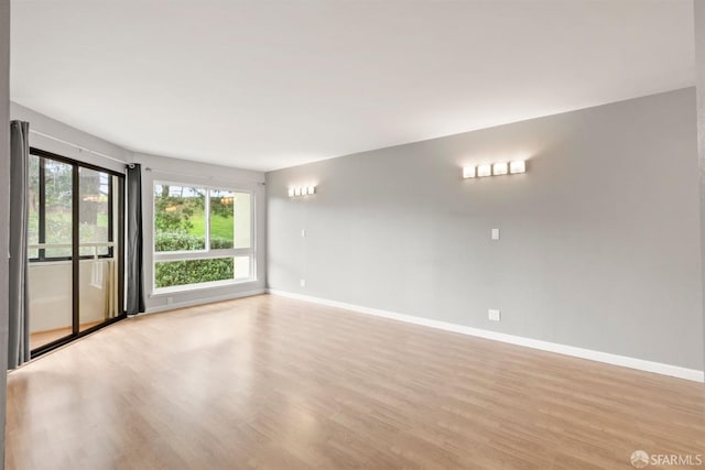 unfurnished room with light wood-type flooring and baseboards