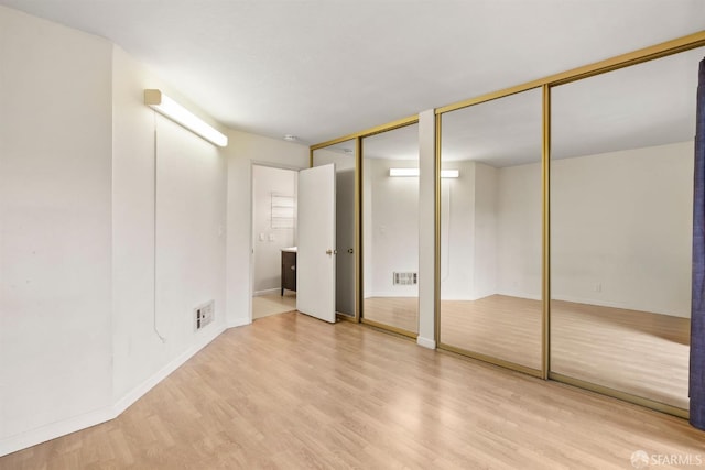 unfurnished bedroom featuring light wood-style floors, visible vents, and two closets