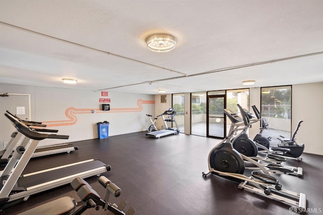 exercise room with floor to ceiling windows and a textured ceiling