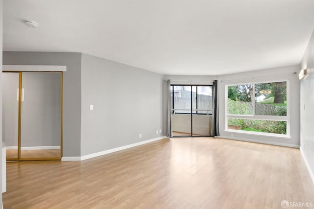 unfurnished room with light wood-type flooring and baseboards