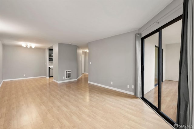 unfurnished room featuring light wood-type flooring, heating unit, and baseboards