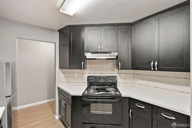 kitchen featuring freestanding refrigerator, light countertops, light wood-type flooring, under cabinet range hood, and black range with electric cooktop